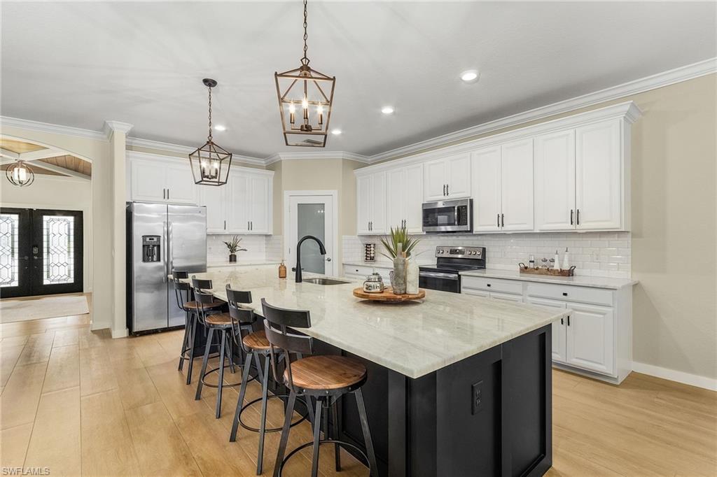 a open kitchen with stainless steel appliances granite countertop a stove top oven a refrigerator a sink dishwasher a dining table and chairs with wooden floor