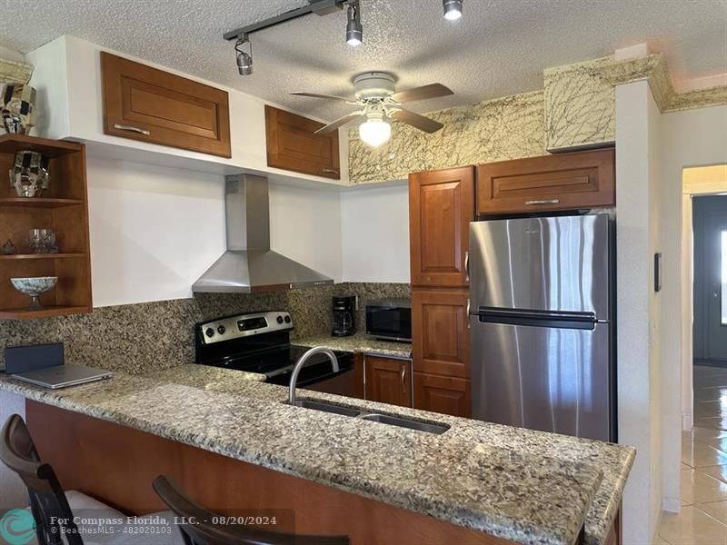 a kitchen with stainless steel appliances granite countertop a sink refrigerator and microwave