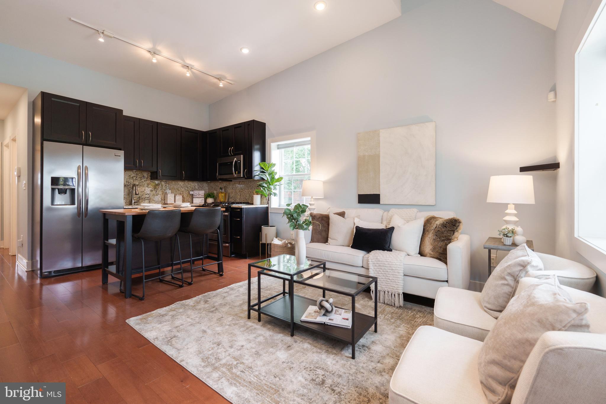 a living room with furniture a wooden floor and a view of kitchen