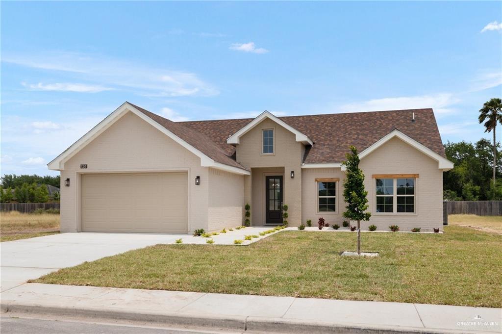 View of front of property with a front yard and a garage