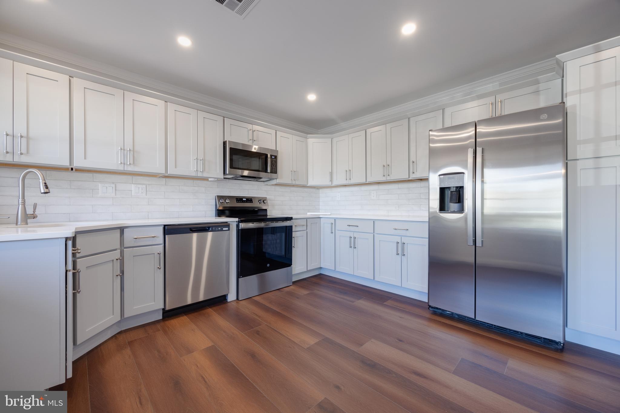 a kitchen with stainless steel appliances granite countertop a refrigerator sink and microwave