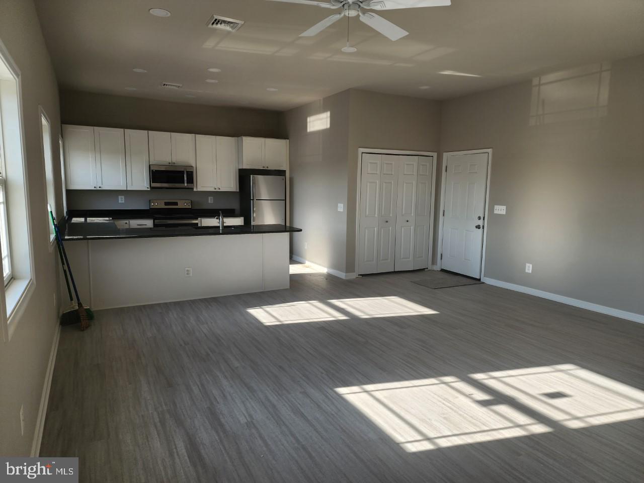 a kitchen with stainless steel appliances wooden floors and view living room