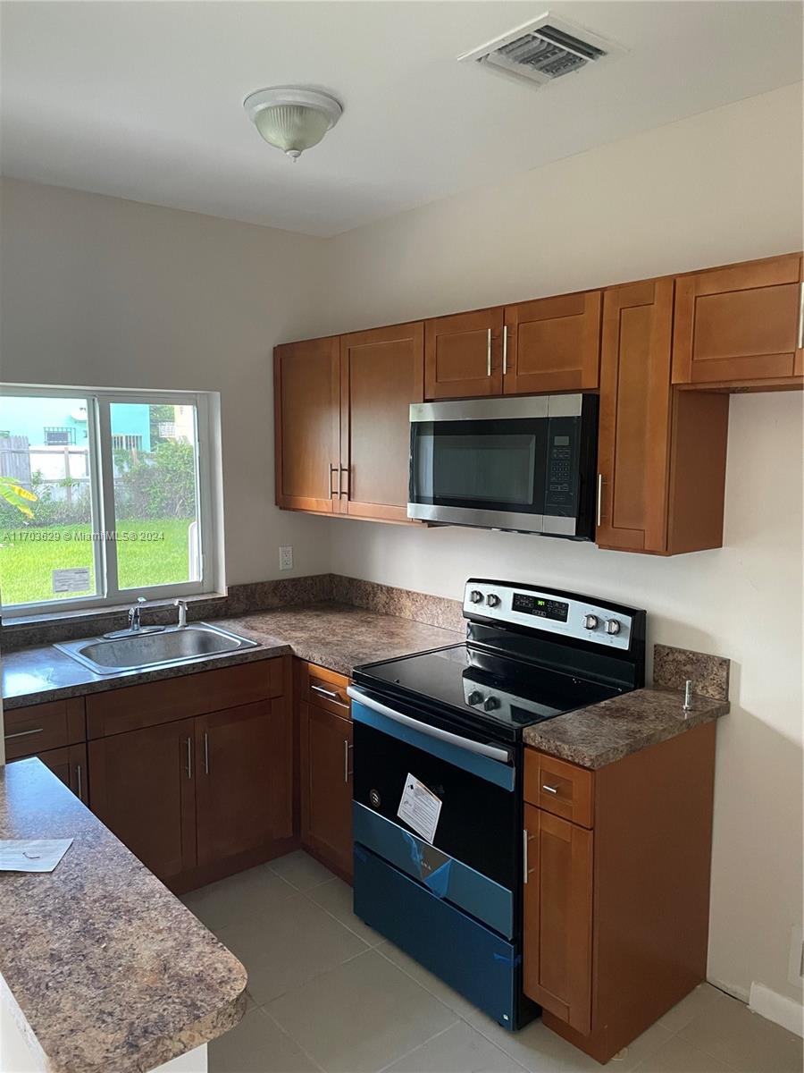 a kitchen with sink a microwave a stove and cabinets