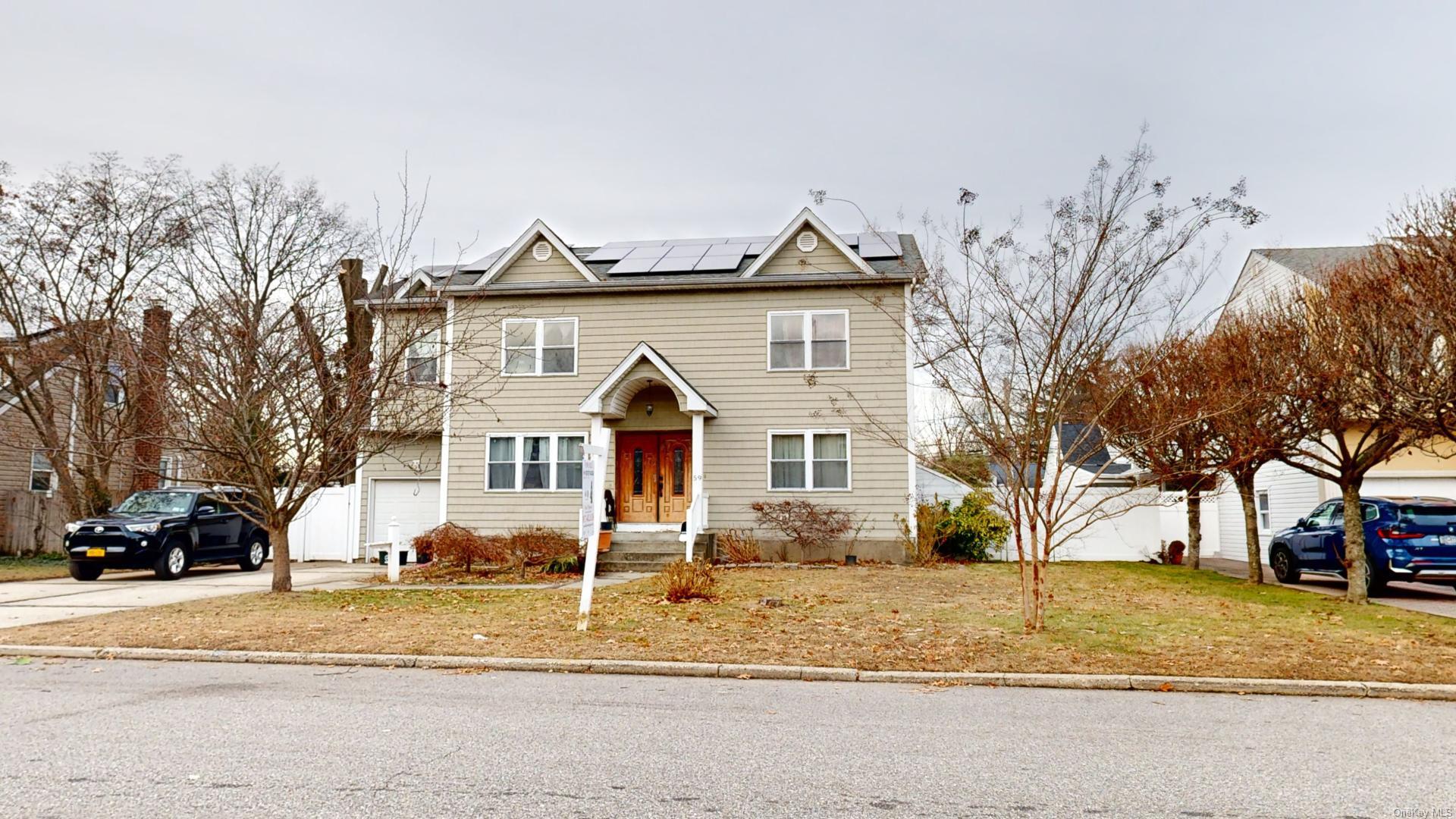 Front of property with a front yard, solar panels, and a garage