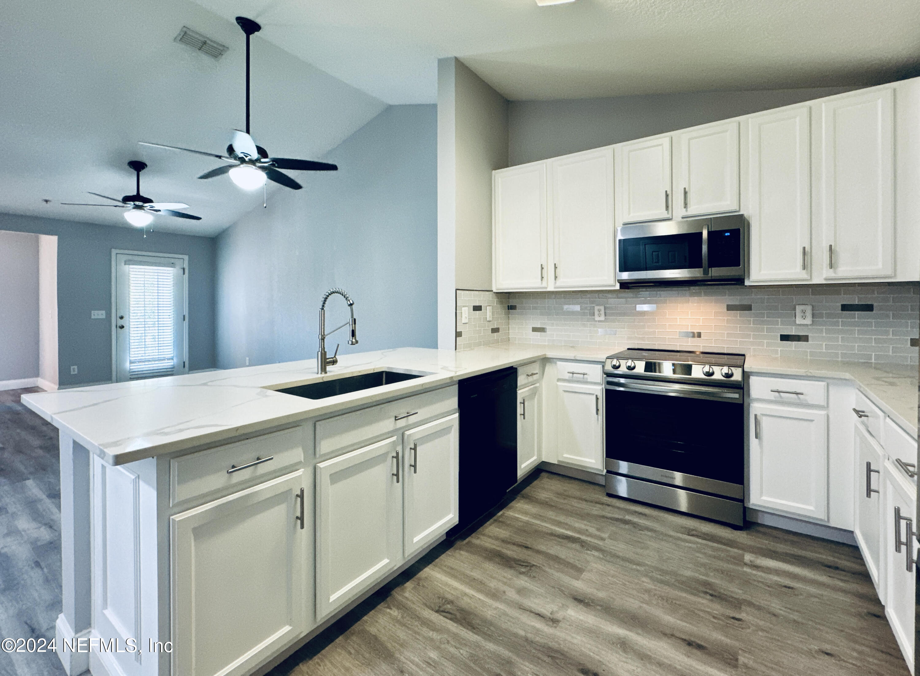 a kitchen with stainless steel appliances granite countertop a sink a stove a microwave and cabinets