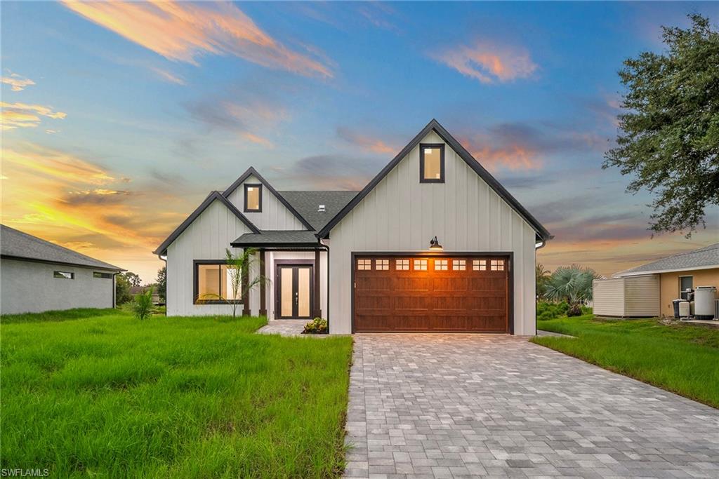 Modern farmhouse style home featuring a garage and a lawn