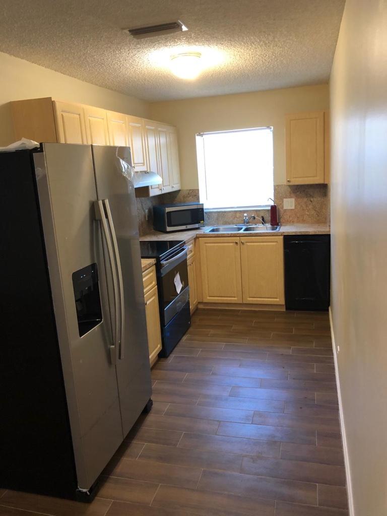 a kitchen with granite countertop a refrigerator and a sink