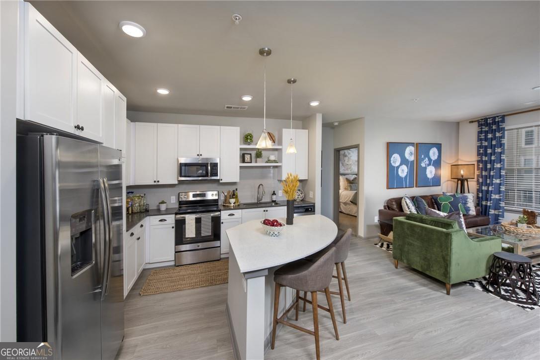 a living room with stainless steel appliances furniture a rug and a kitchen view