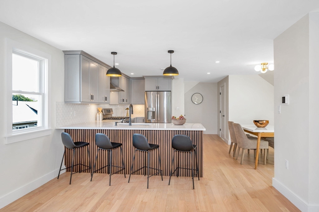 a kitchen with a dining table chairs and wooden floor