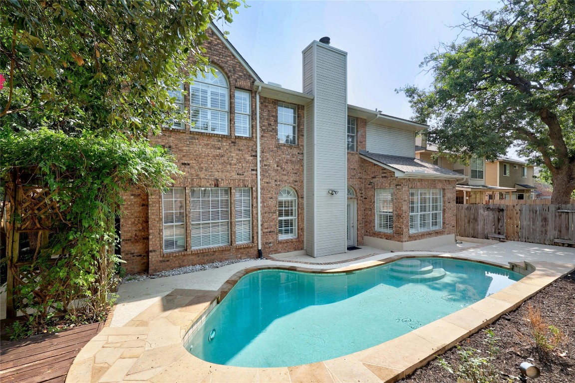 a view of a house with brick walls plants and large tree