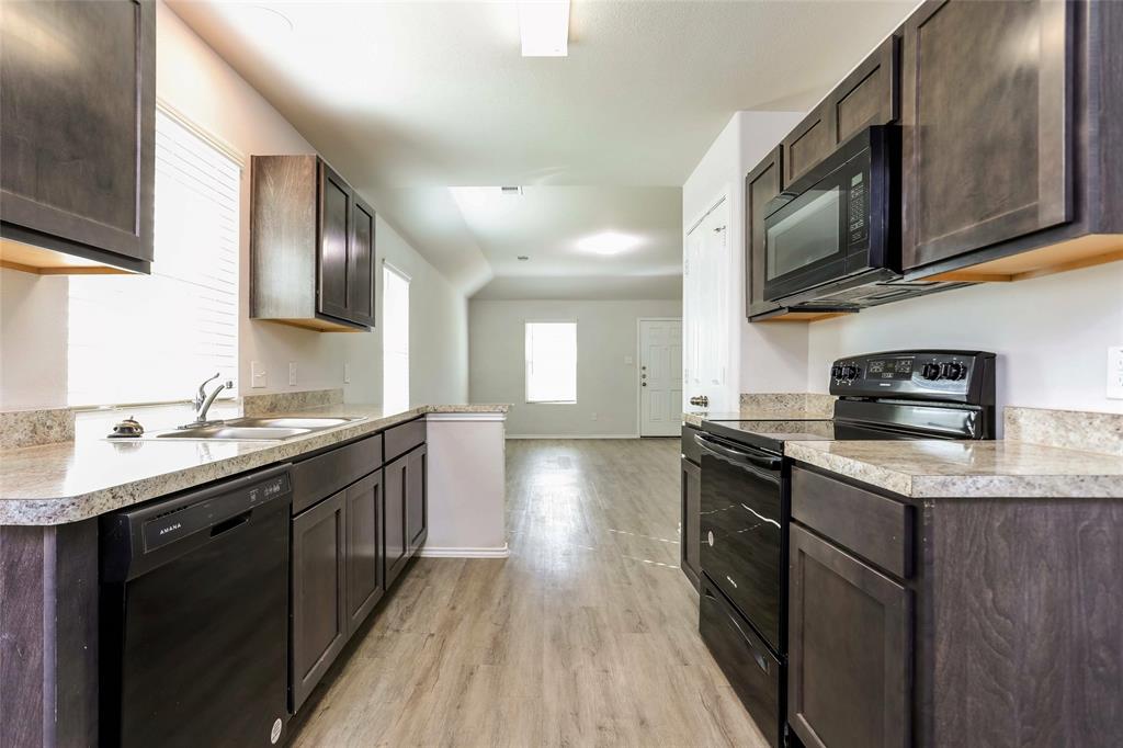 a kitchen with stainless steel appliances granite countertop a sink a stove top oven a counter space and cabinets