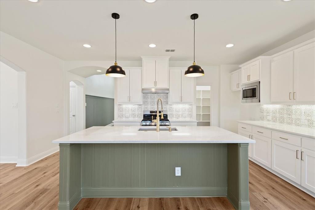 a kitchen with kitchen island white cabinets and stainless steel appliances