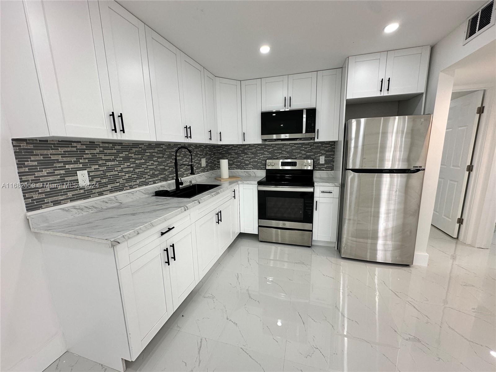 a kitchen with granite countertop a refrigerator sink and cabinets