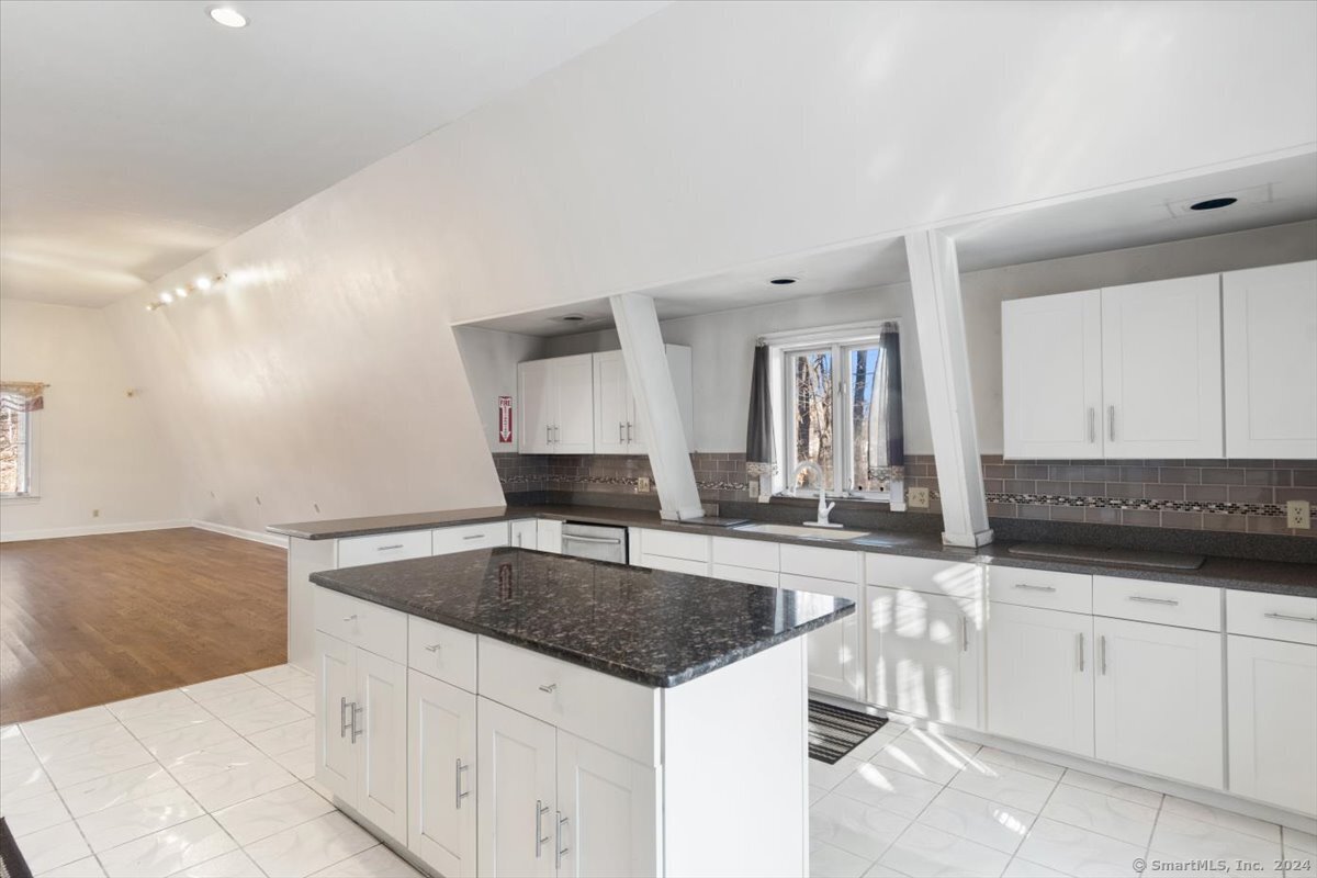 a kitchen with granite countertop a sink and white cabinets