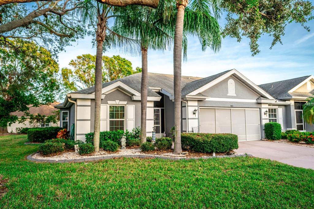 a view of a white house next to a yard with palm trees