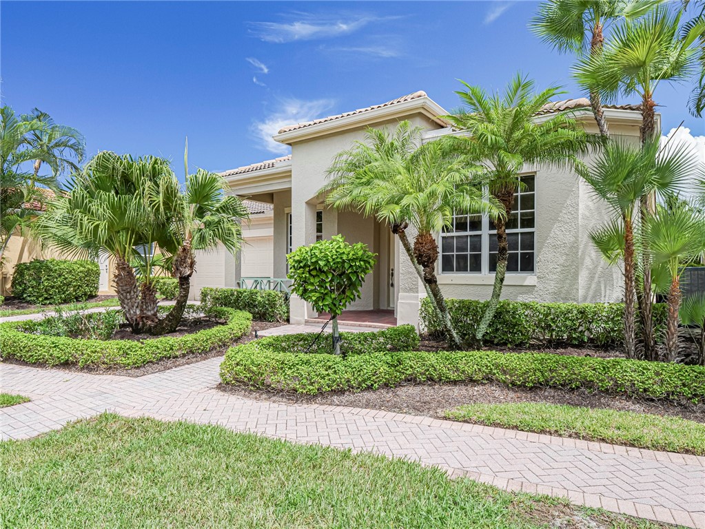 a front view of a house with a yard and potted plants