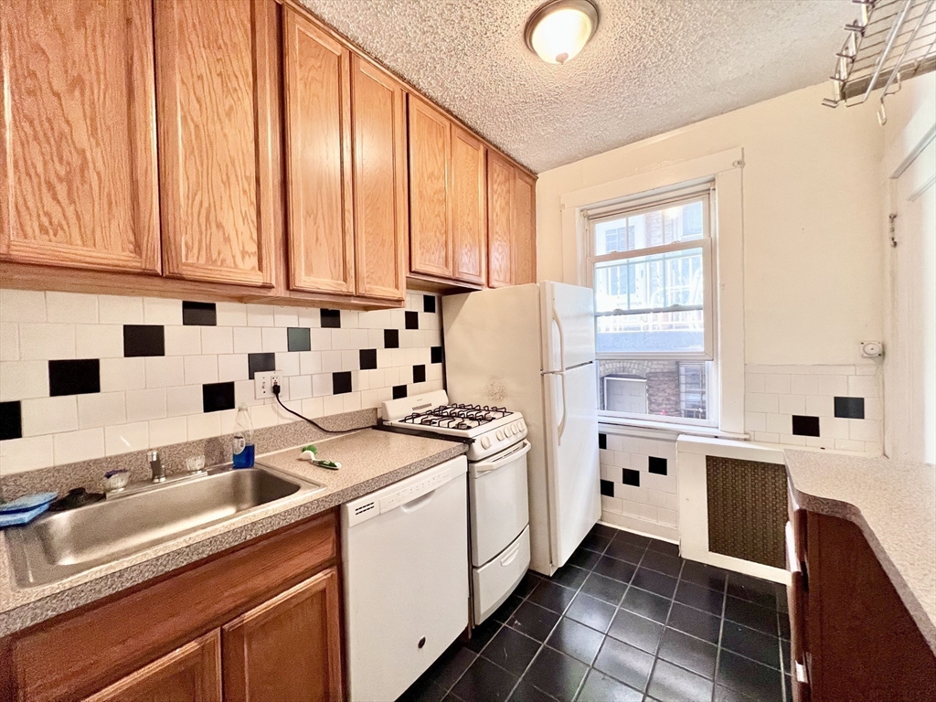 a kitchen with a sink a stove and white cabinets