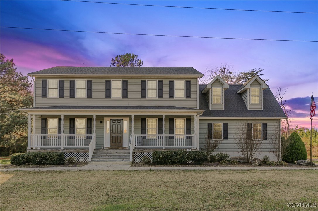 Colonial-style house featuring a porch and a yard