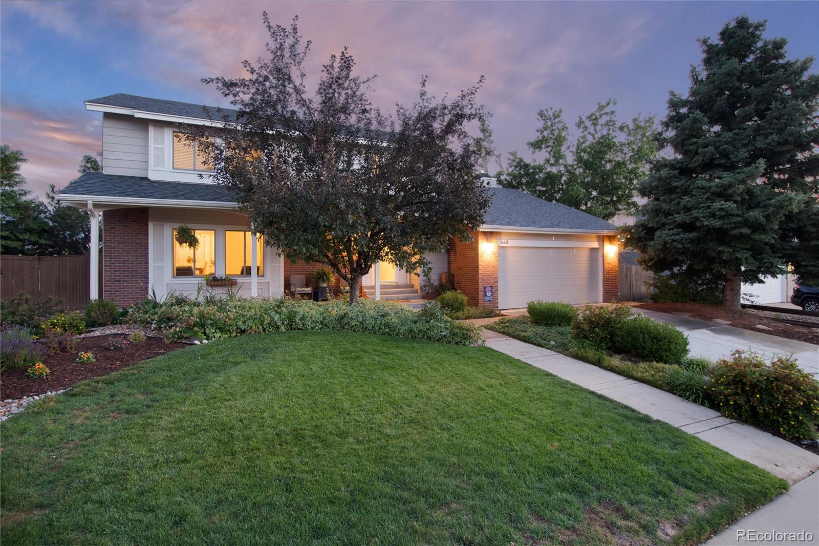 a front view of a house with garden and trees