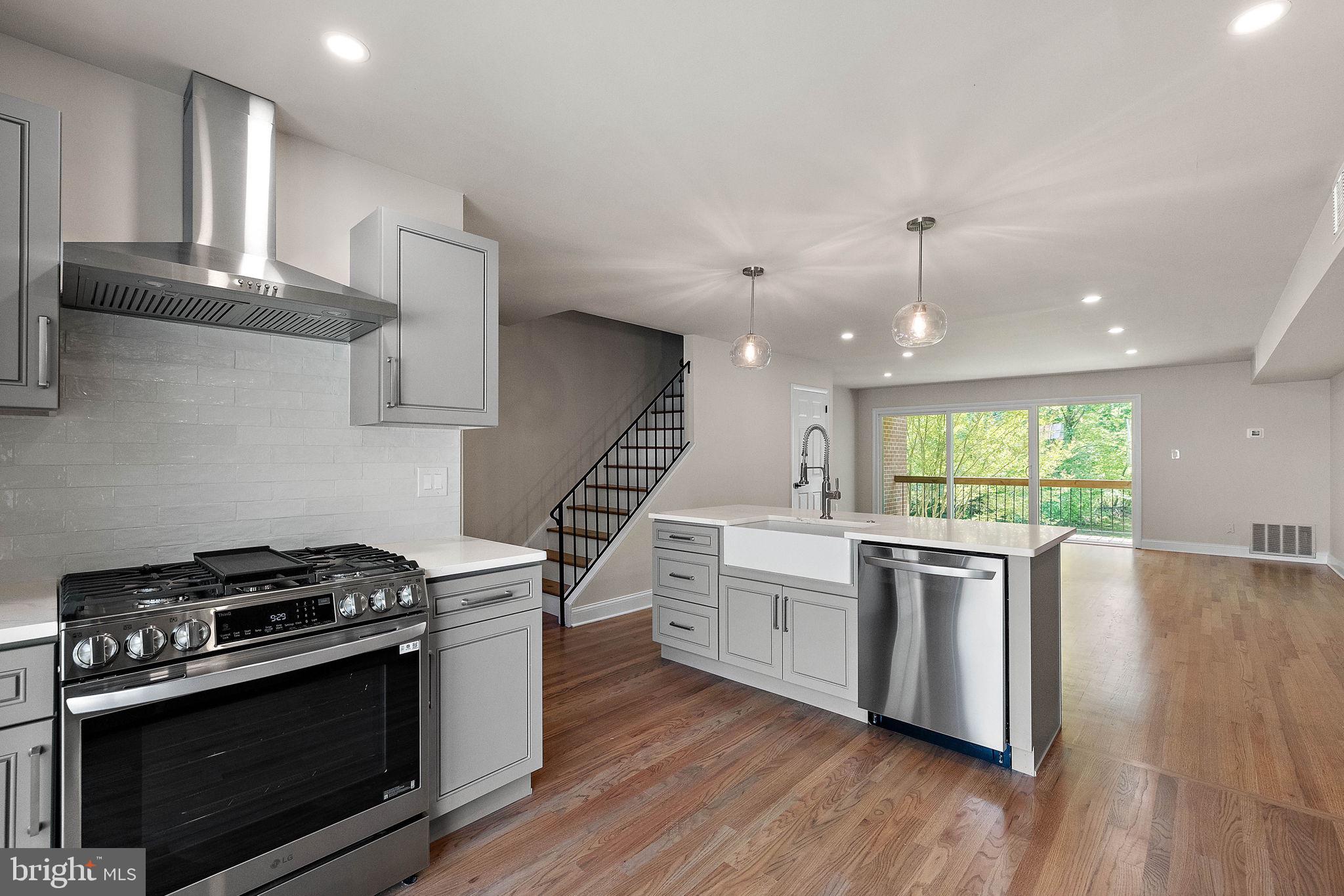 a kitchen with stainless steel appliances a stove a sink and wooden floors