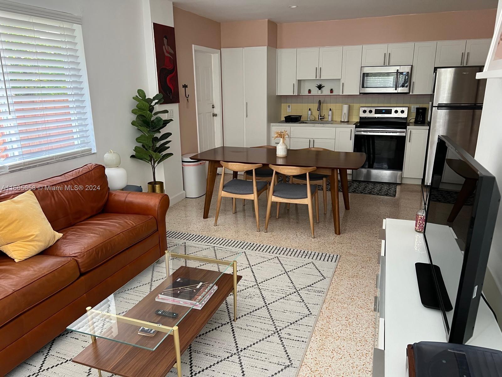 a living room with stainless steel appliances furniture a dining table and a potted plant