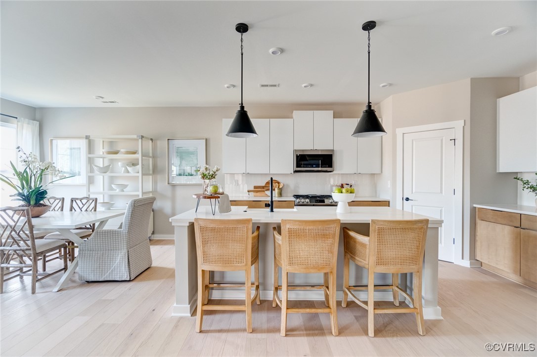 a kitchen with stainless steel appliances kitchen island granite countertop a dining table chairs and white cabinets