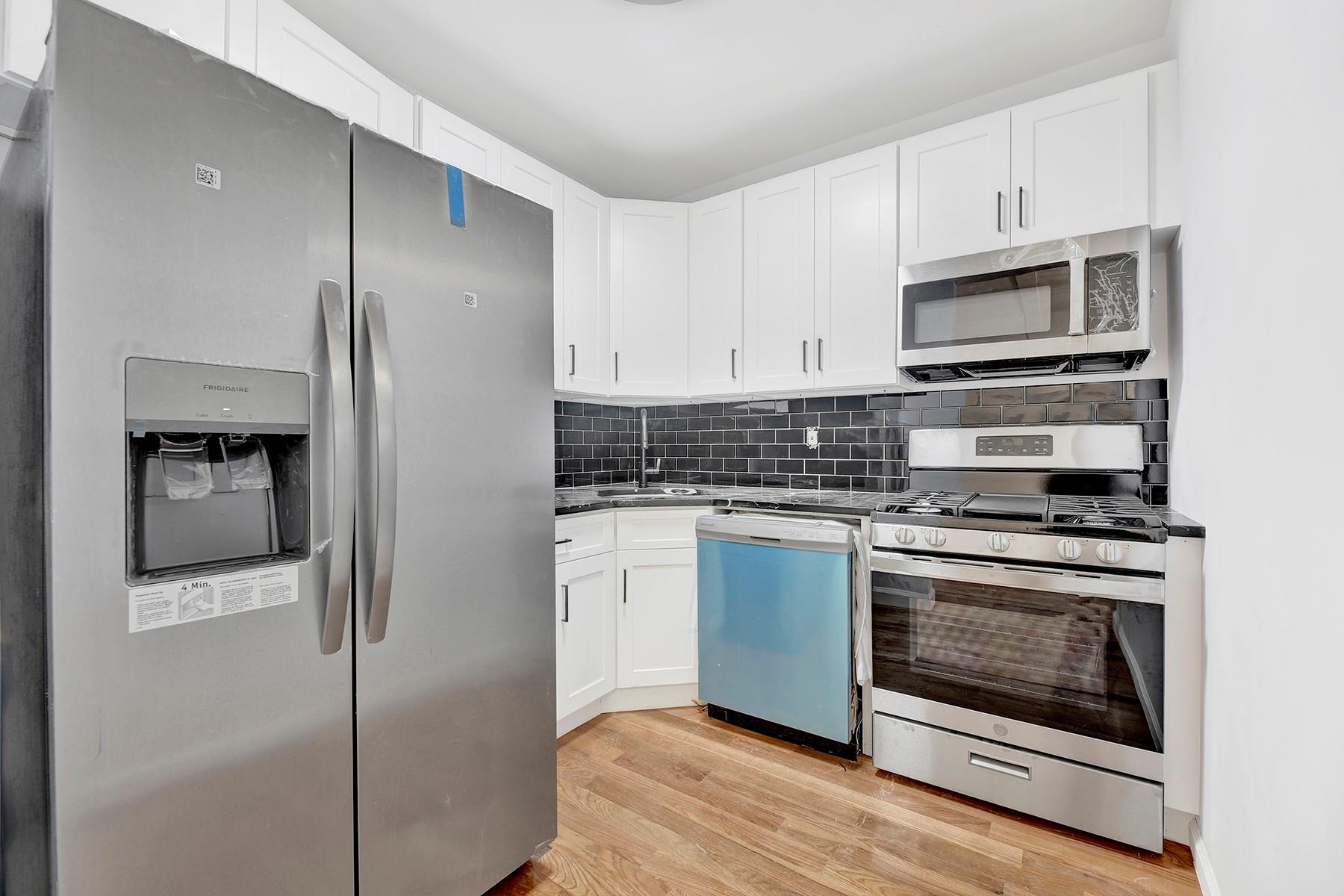 Kitchen with sink, tasteful backsplash, light hardwood / wood-style floors, white cabinetry, and stainless steel appliances