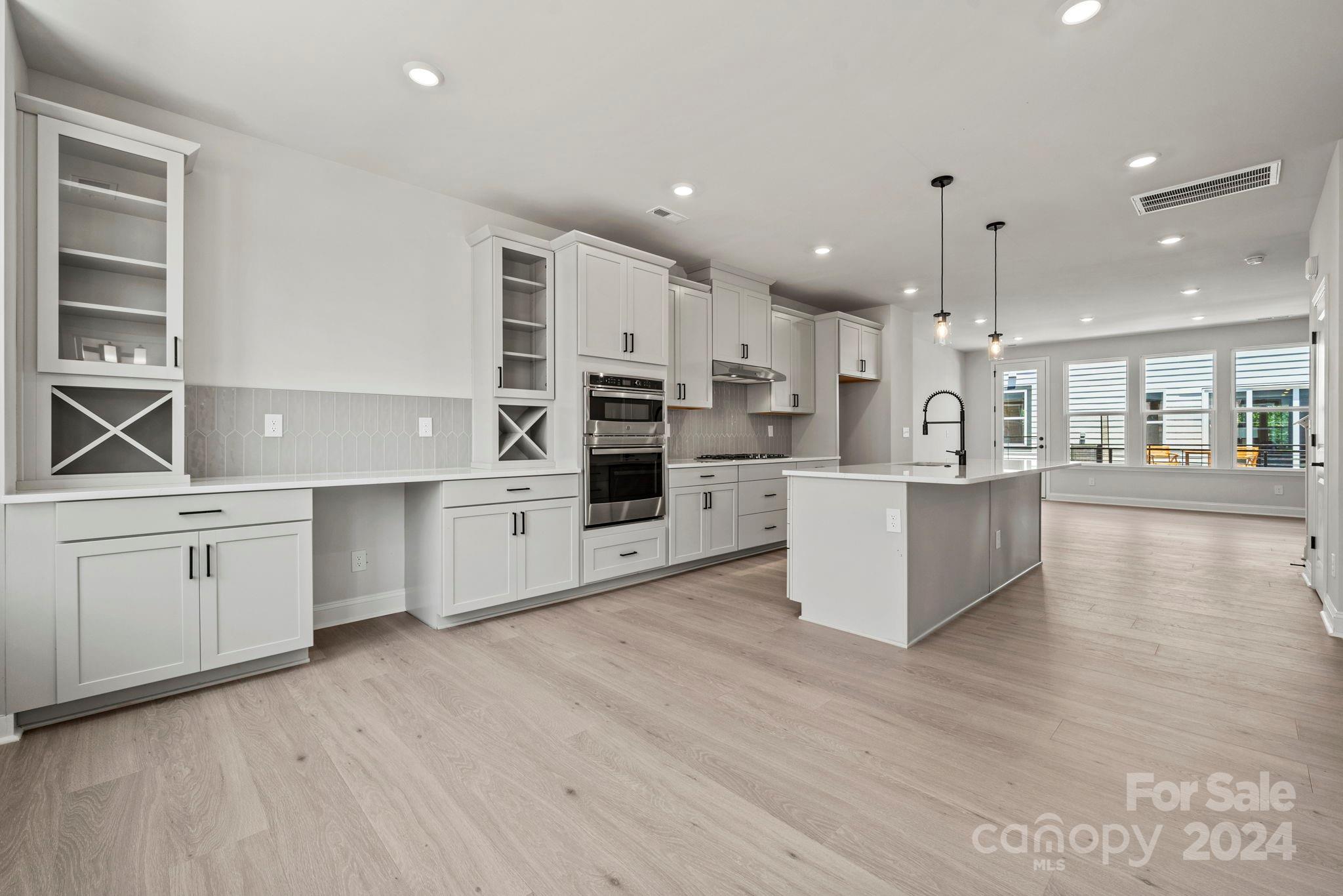 a kitchen with stainless steel appliances kitchen island wooden floors and white cabinets