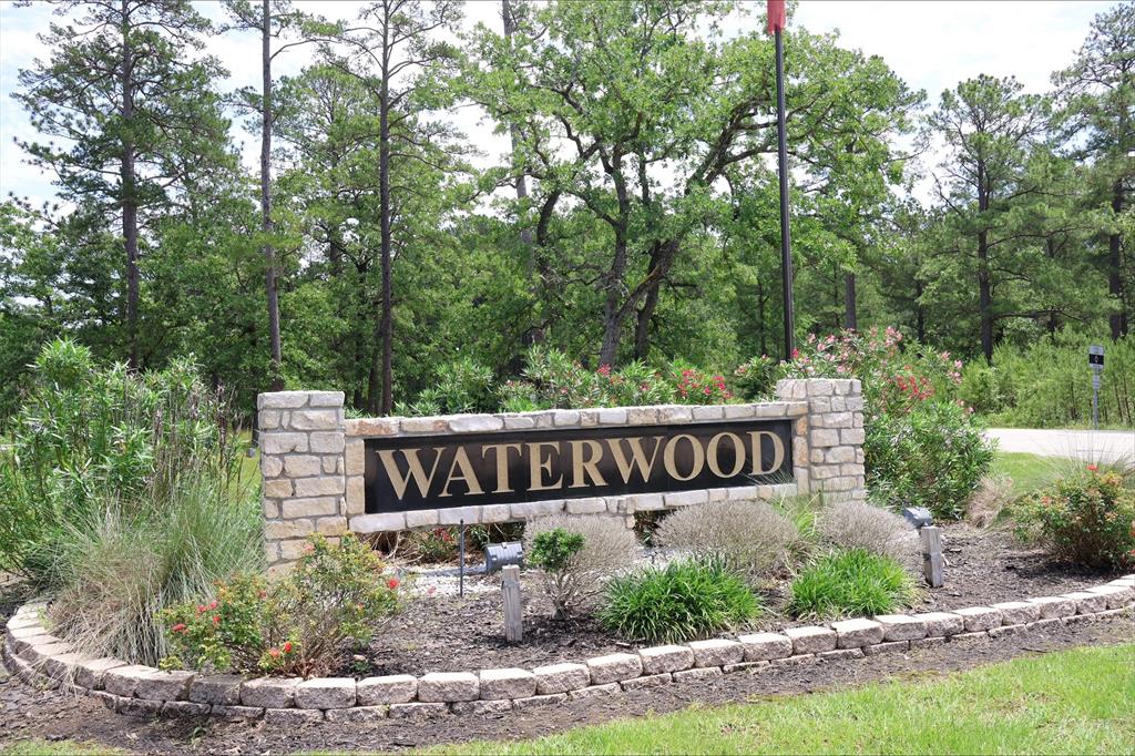 a view of sign board with yard and trees around