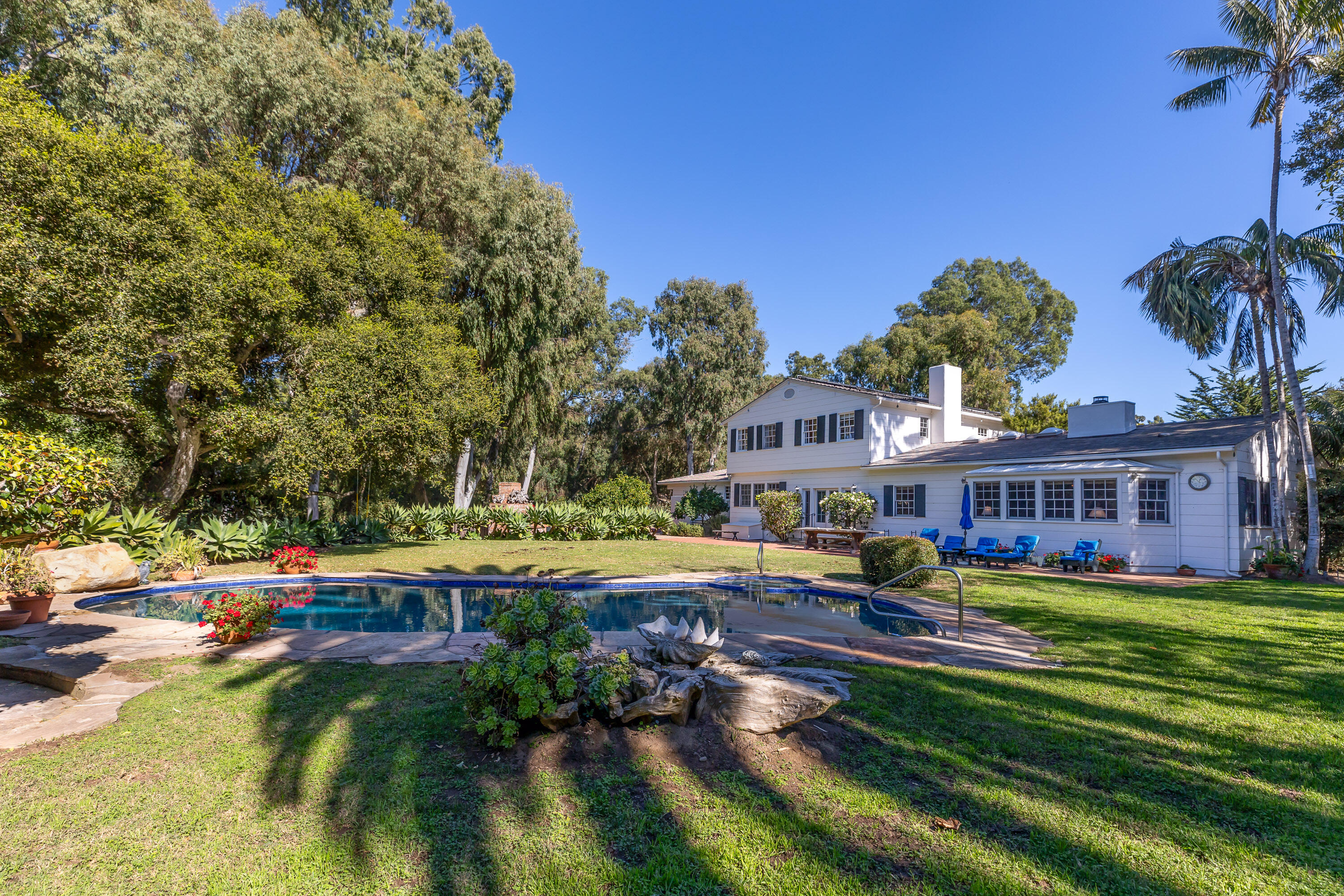 a view of swimming pool with lawn chairs and plants