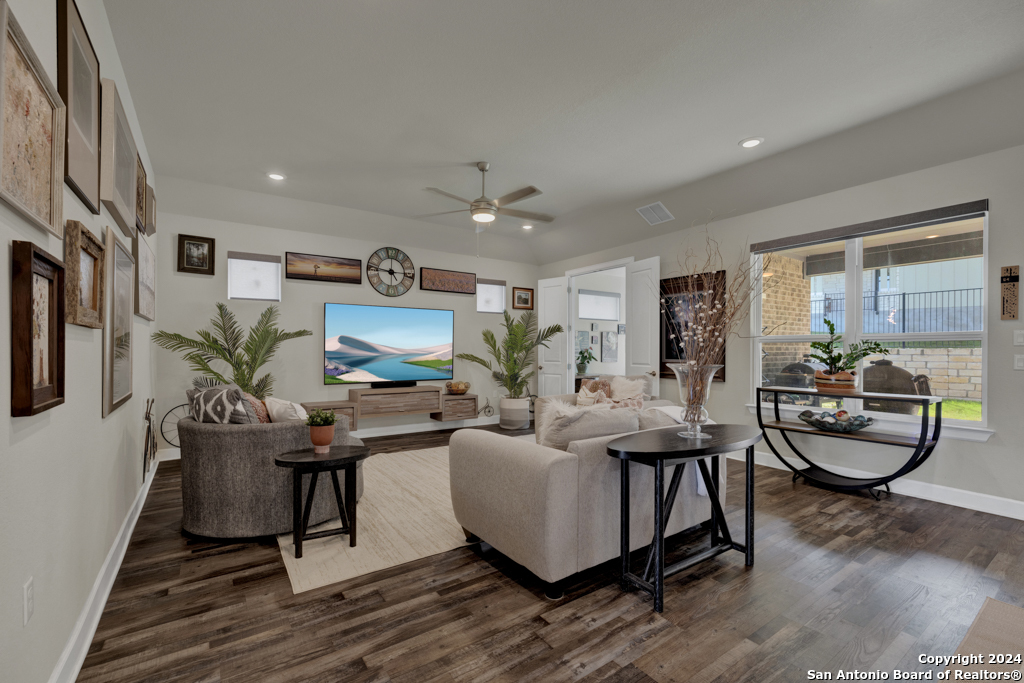 a living room with furniture a large window and wooden floor