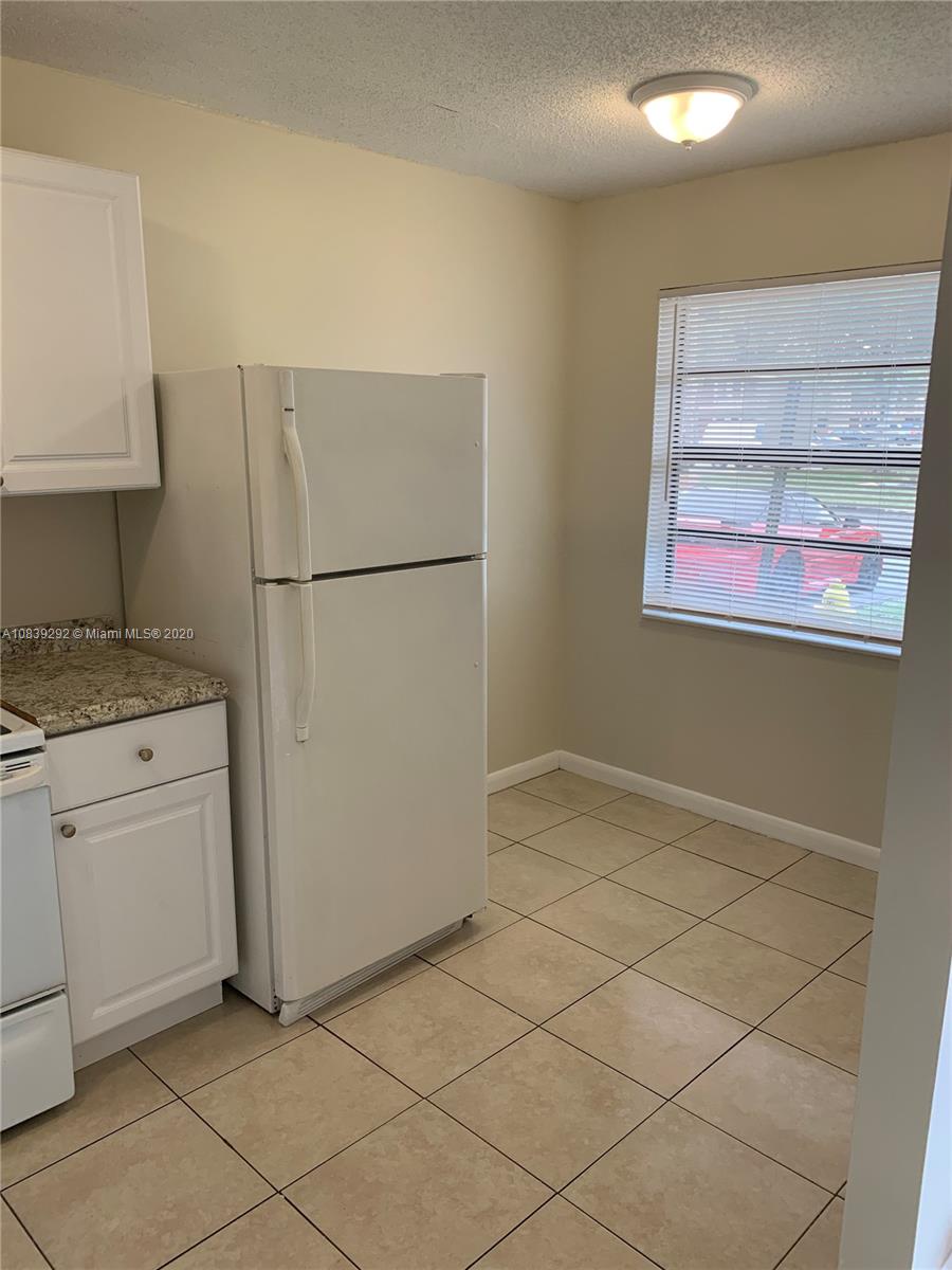 a view of kitchen with refrigerator and white cabinets