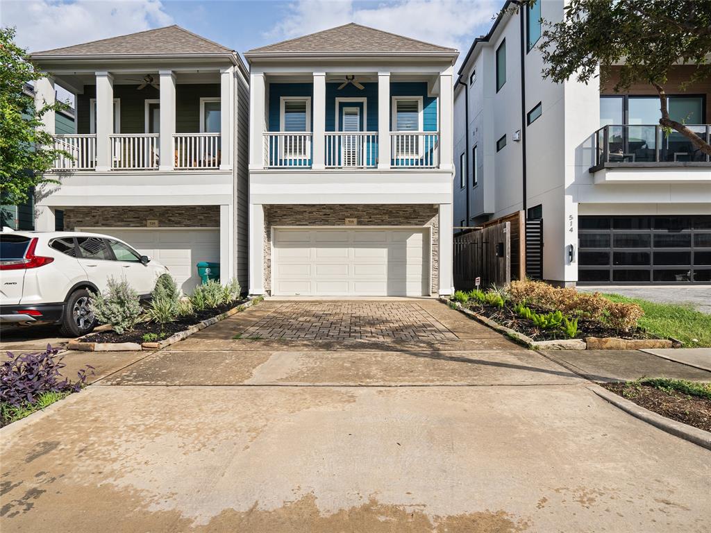 Modern two-story home featuring a balcony, an attached garage, and a private driveway. The exterior has a mix of traditional and contemporary design elements.