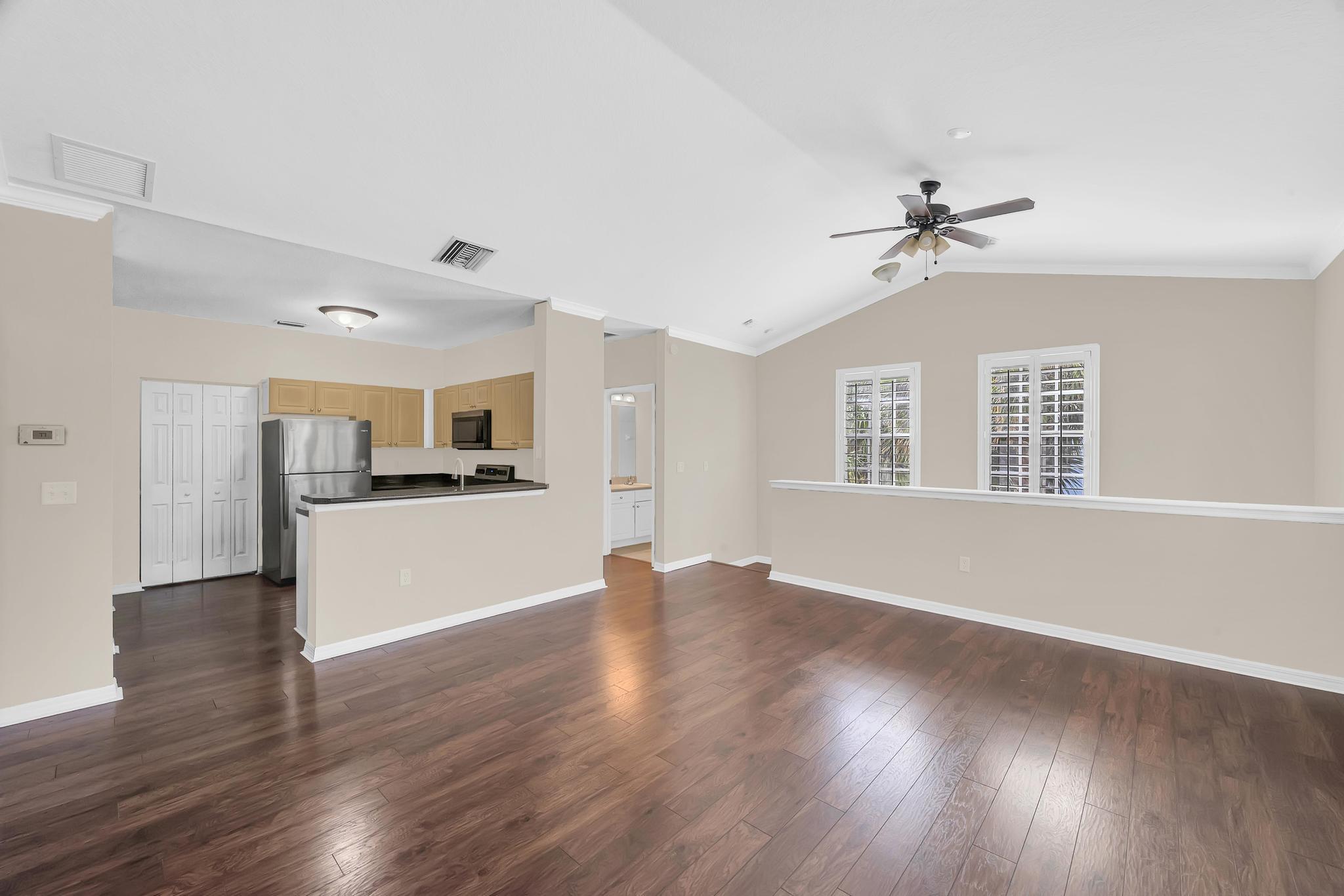 a view of a kitchen with a sink a refrigerator and wooden floor