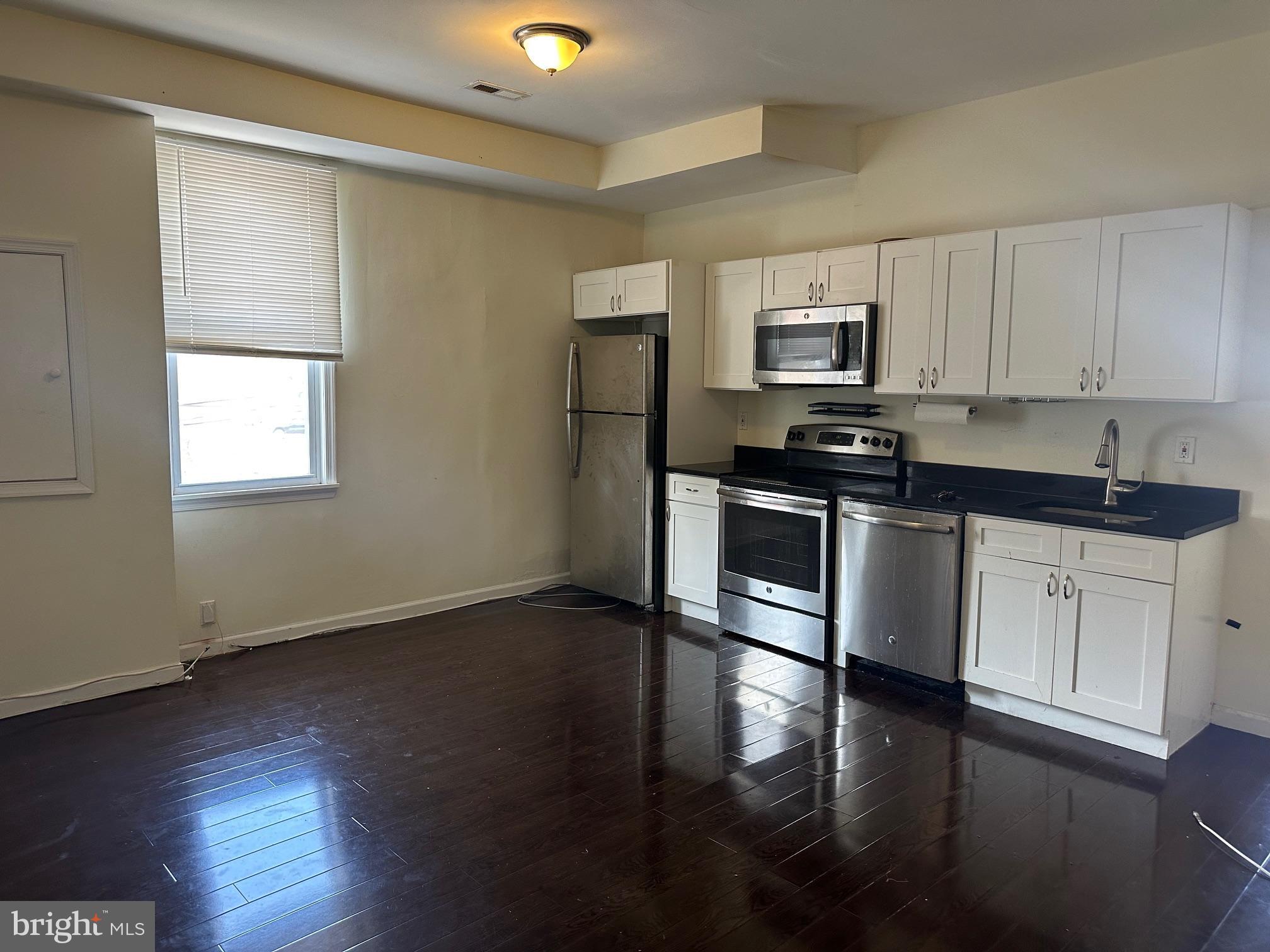 a kitchen with granite countertop a sink cabinets and stainless steel appliances