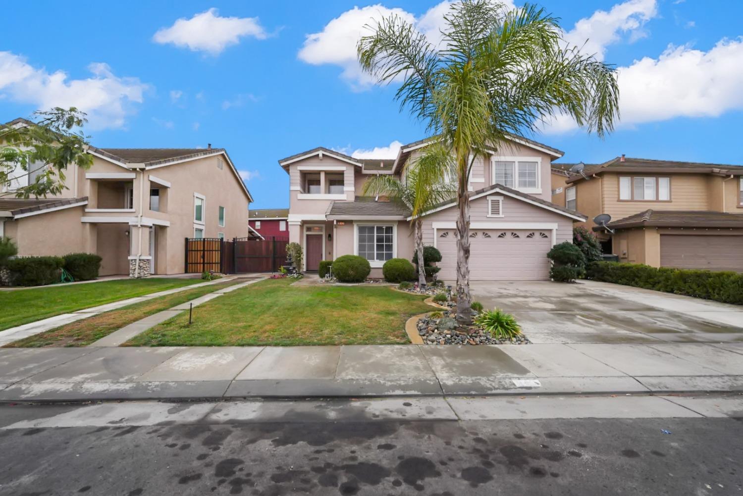 a front view of a house with a yard and palm trees