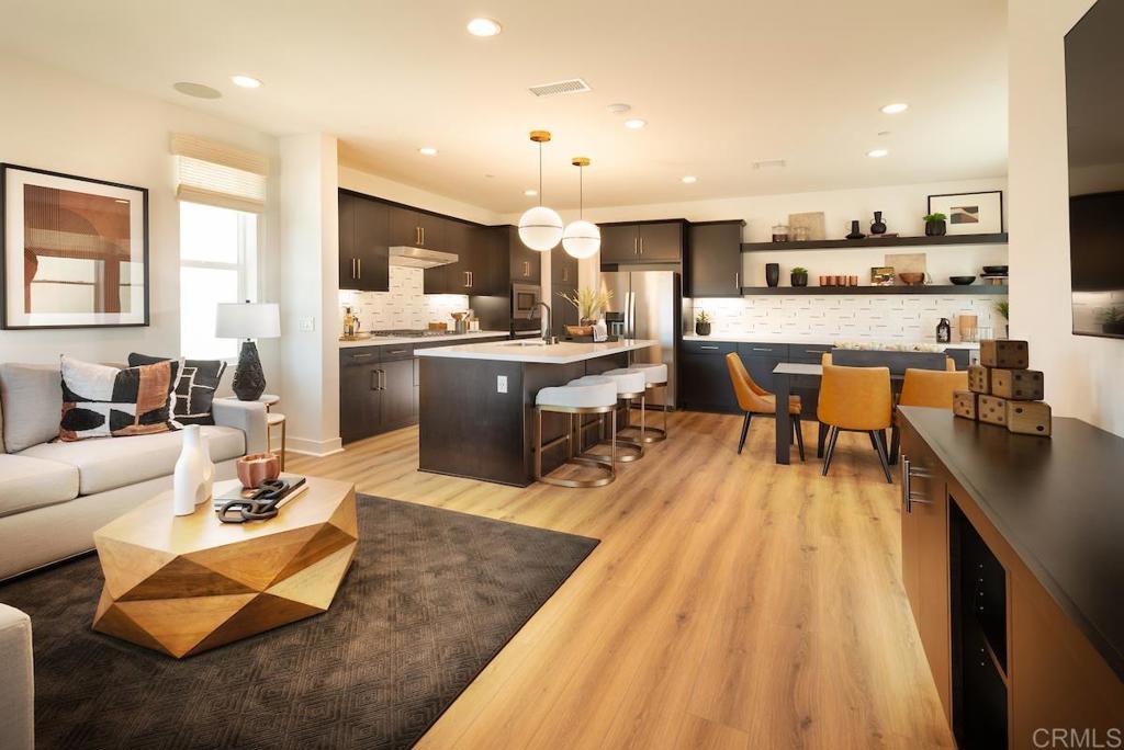 a living room with stainless steel appliances kitchen island granite countertop furniture a rug kitchen view and a living room view