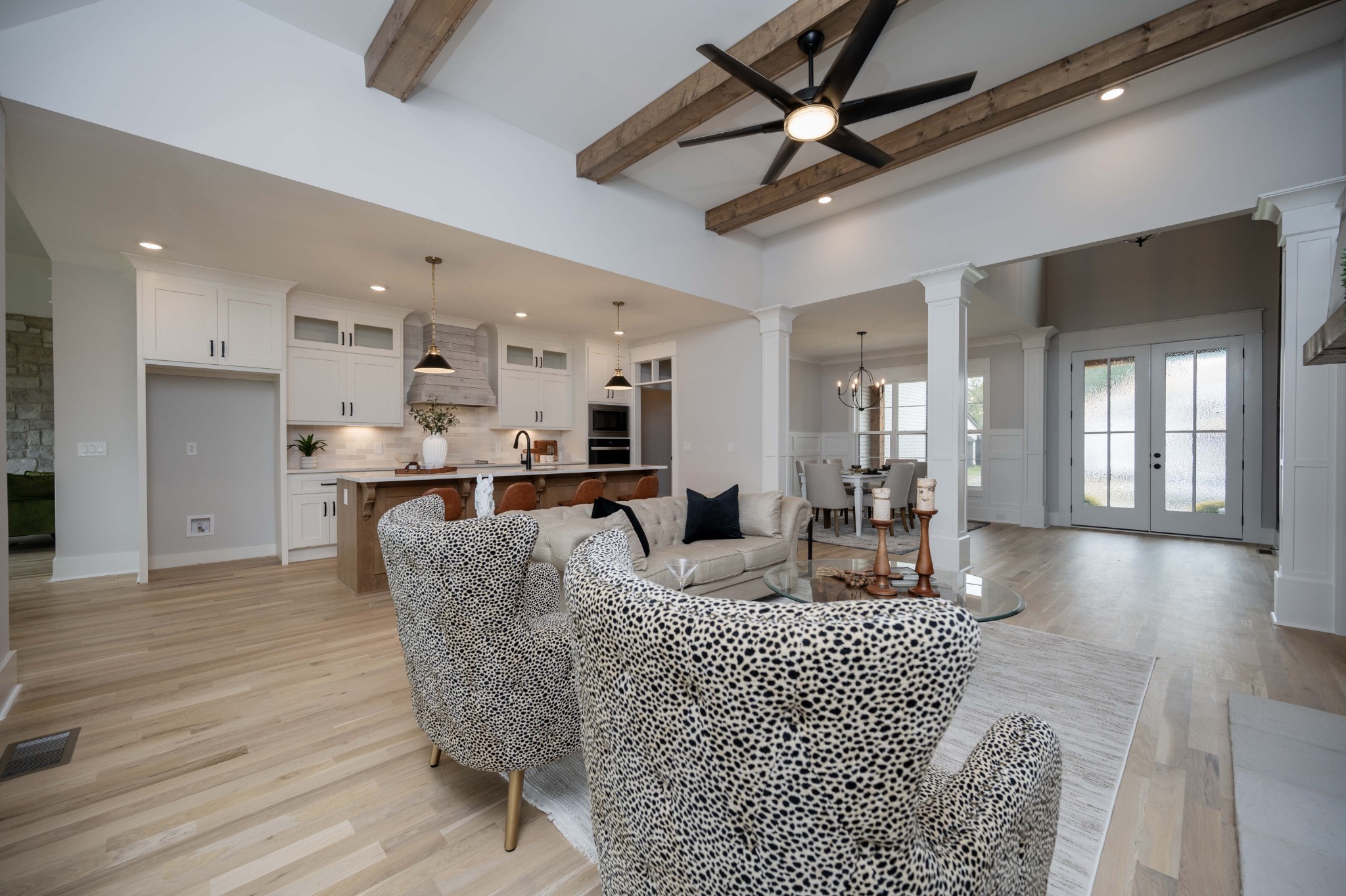 a living room with furniture kitchen view and a wooden floor