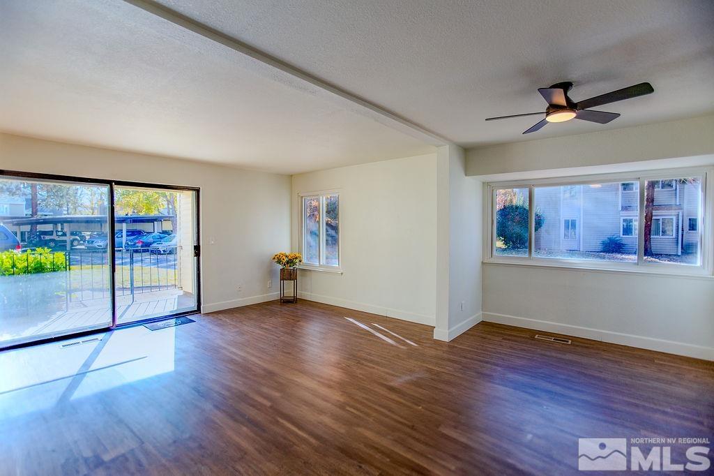 a view of an empty room with a window and wooden floor