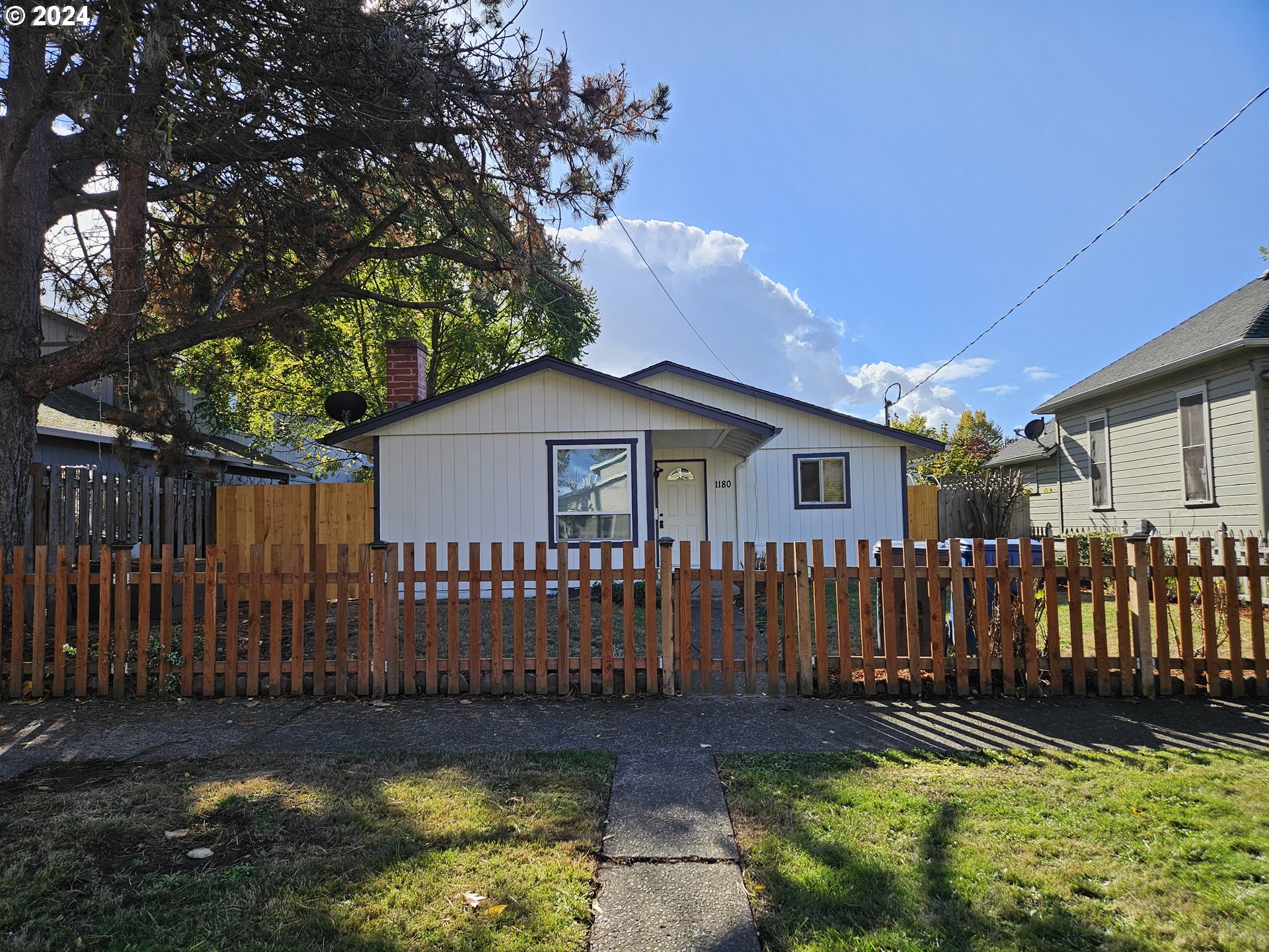 a view of a house with wooden fence and a large tree