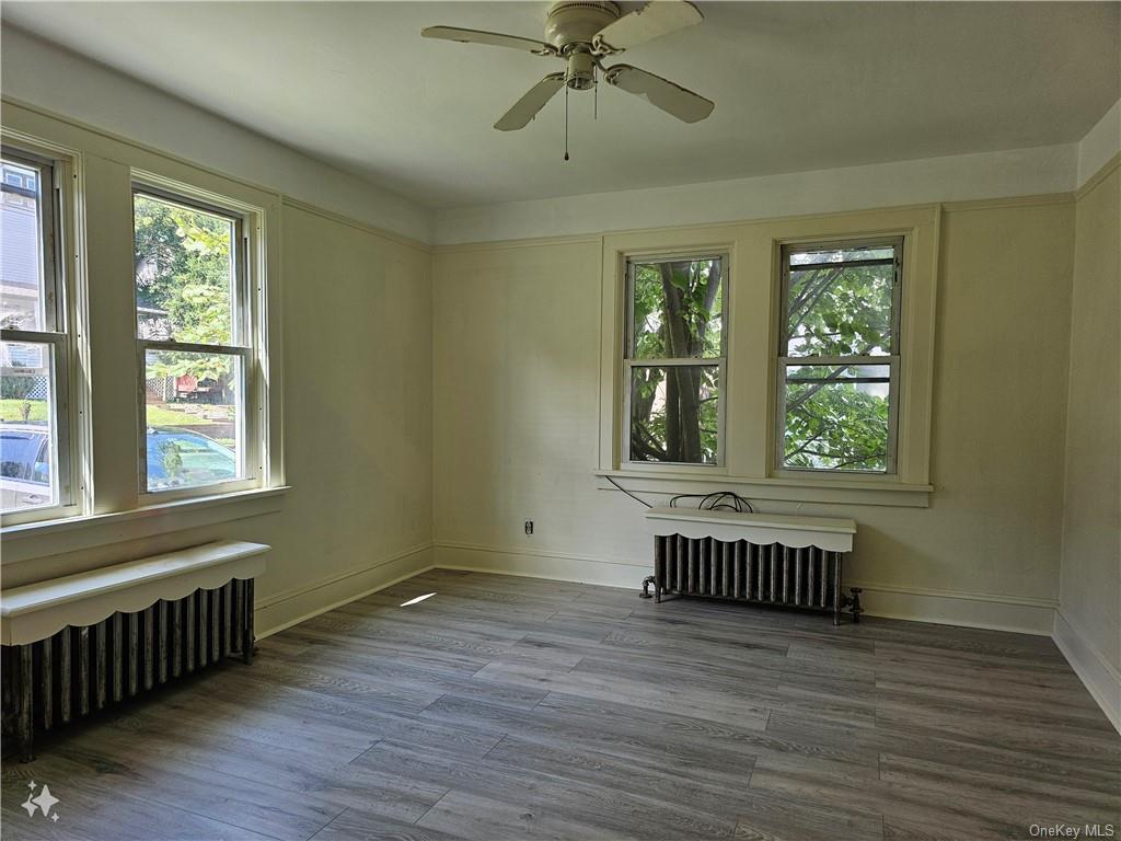 an empty room with wooden floor fan and windows