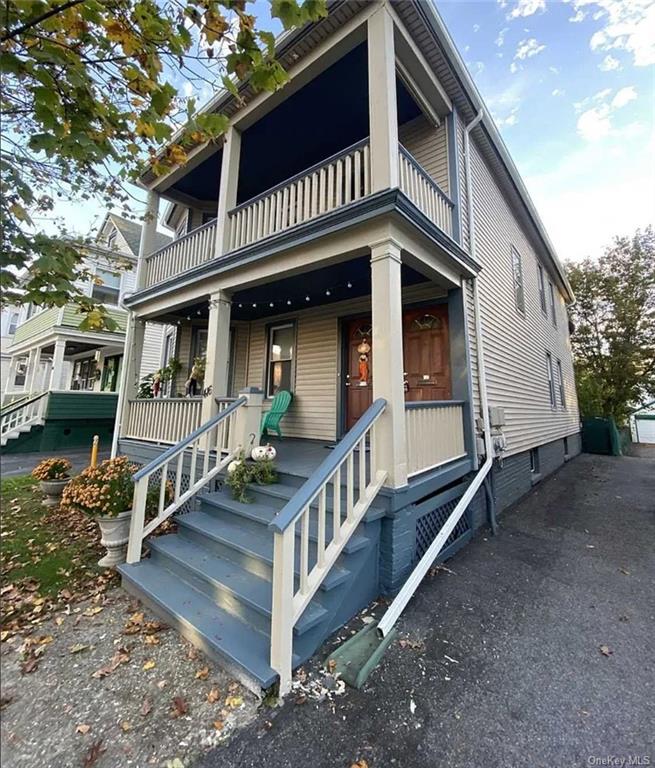 a view of house and small deck with a car park side of the road