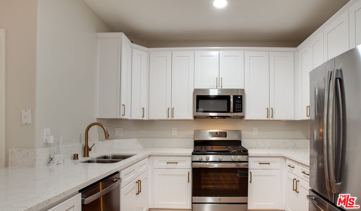 a kitchen with granite countertop white cabinets and stainless steel appliances