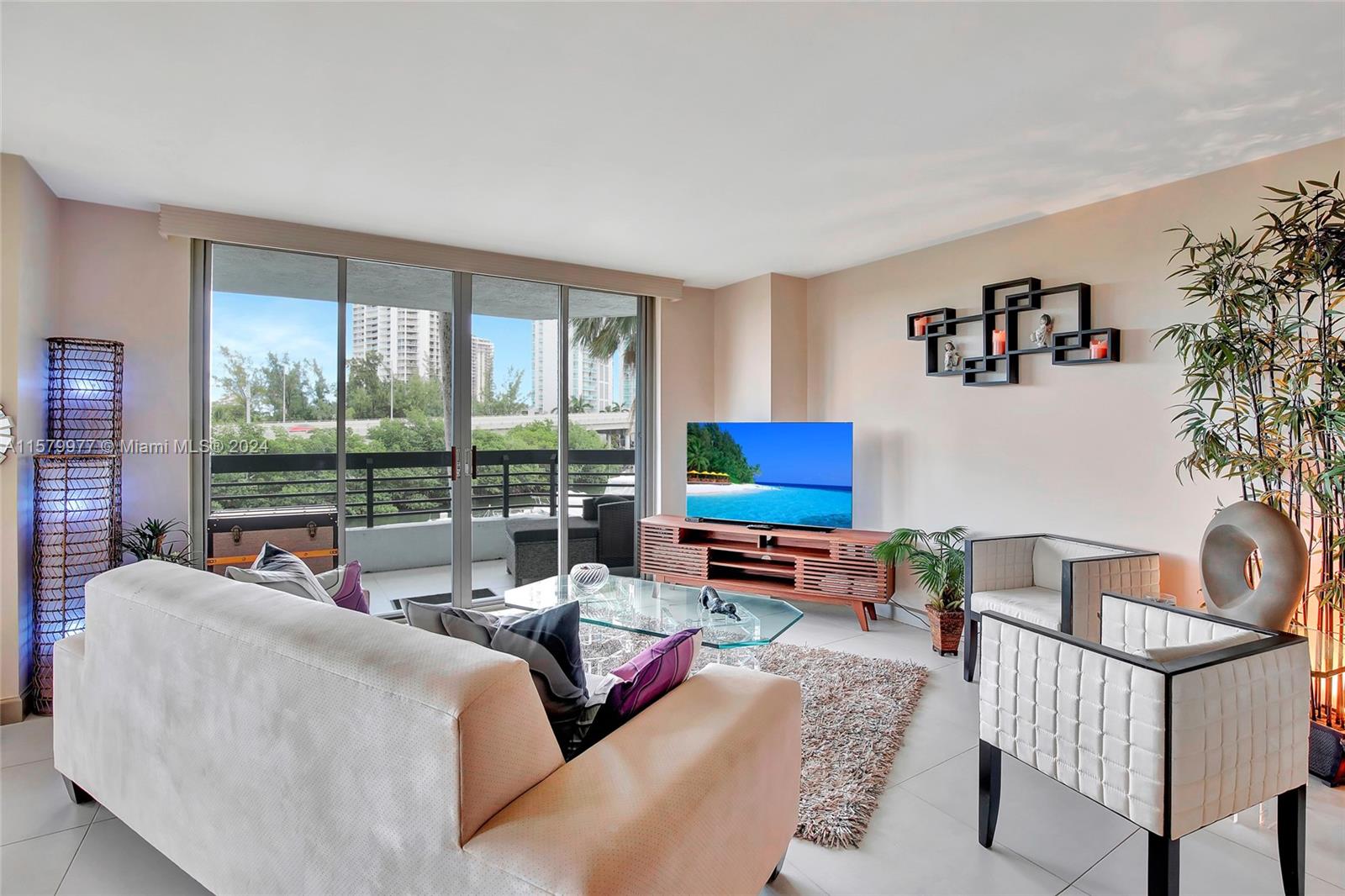 a living room with furniture a flat screen tv and a floor to ceiling window