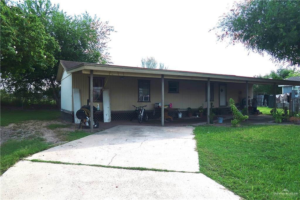 View of front facade with a front lawn and a carport