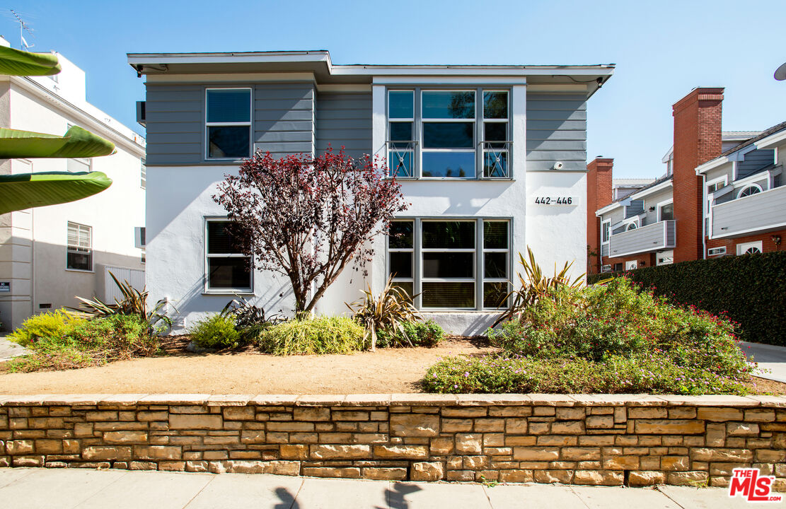 a front view of a house with a yard and potted plants