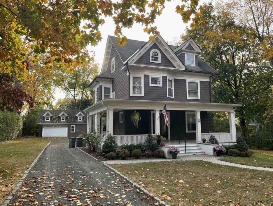 View of front of home with a porch, a front lawn, an outdoor structure, and a garage