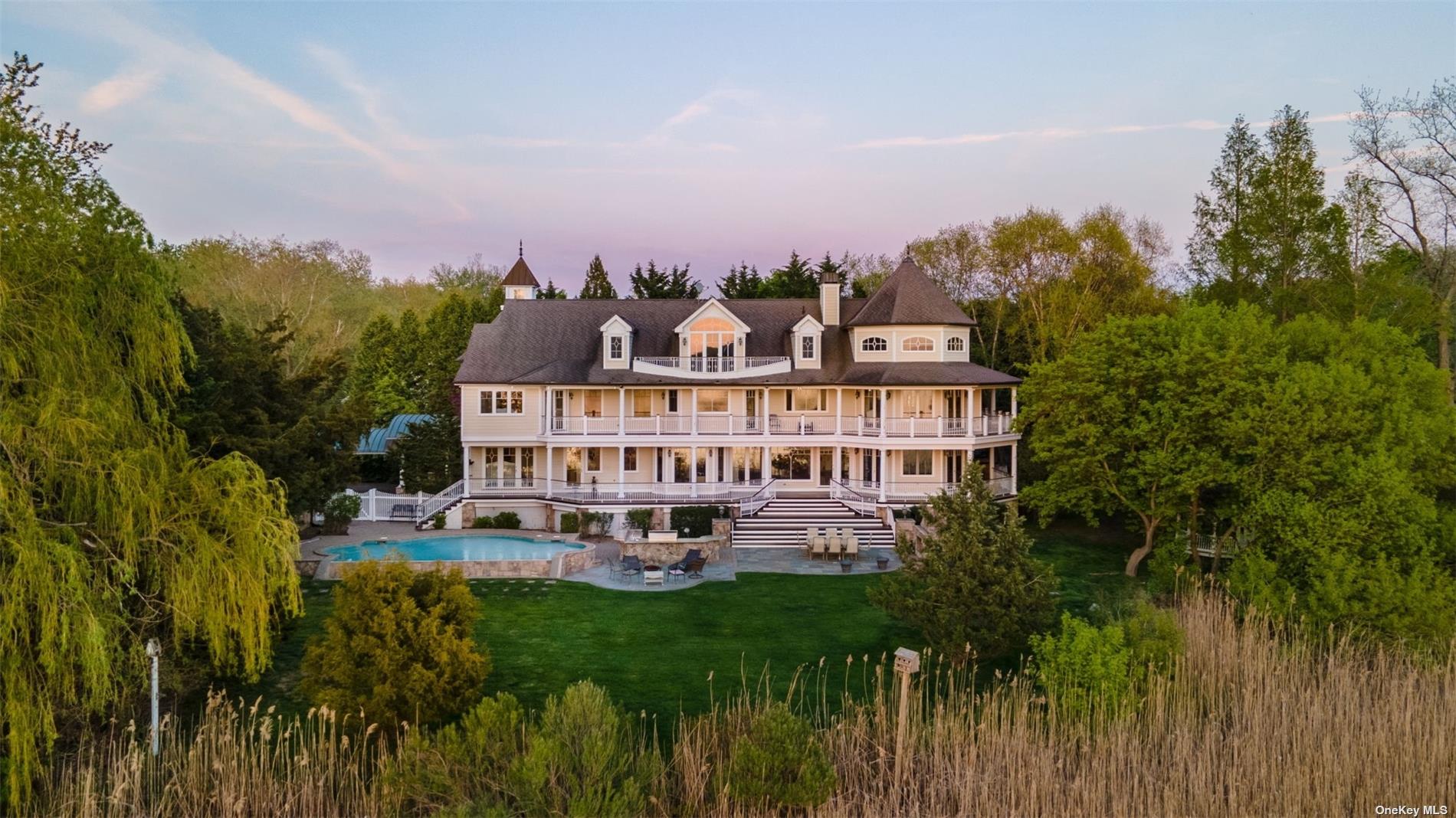 a view of a big house with a big yard and large trees