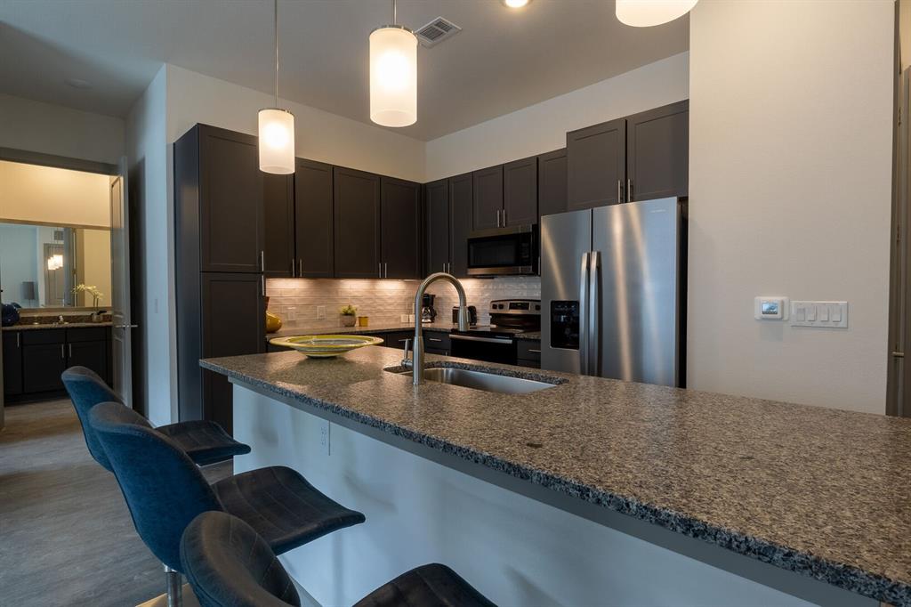 a kitchen with kitchen island granite countertop a sink refrigerator and cabinets