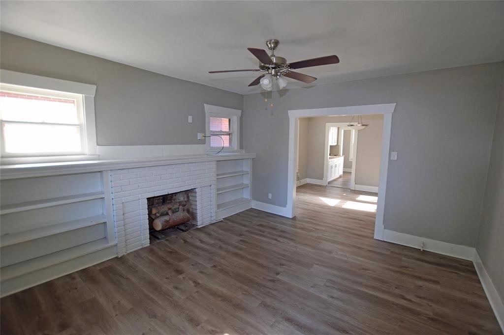 a view of a livingroom with a fireplace window and wooden floor